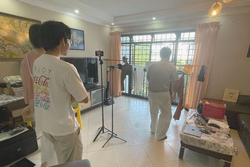 A person shifting items in a room for filming.