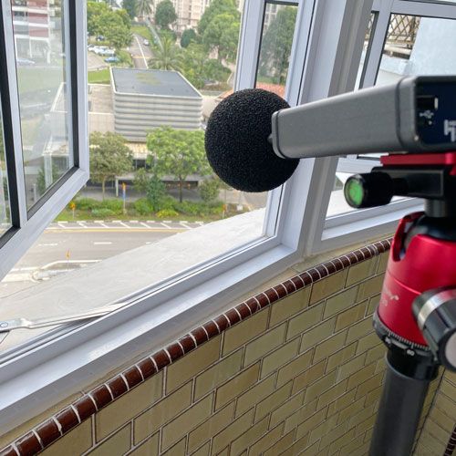The sound meter on the tripod facing the road from an open window