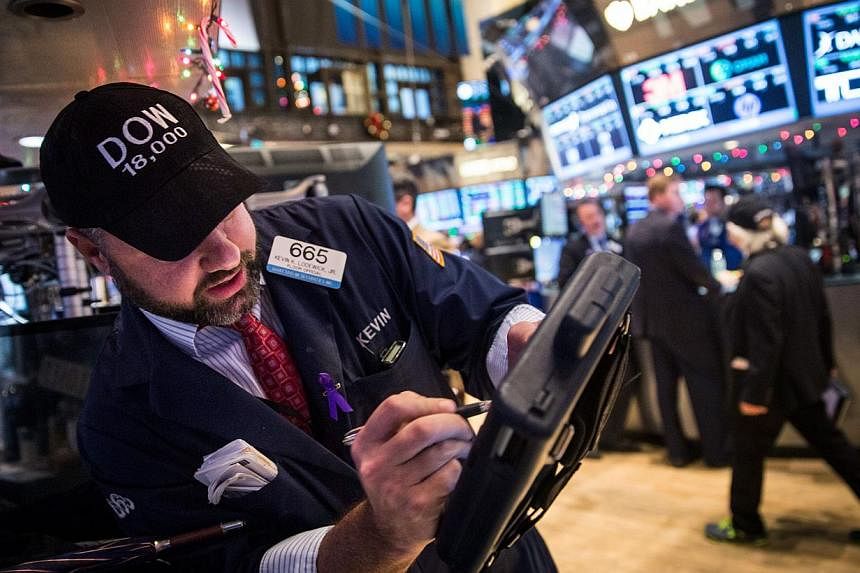 Traders wear hats that say "DOW 18,000" as they work on the floor of the New York Stock Exchange Tuesday afternoon in New York City. The Dow Jones Industrial Average crossed a landmark by closing above 18,000 points. -- PHOTO: AFP