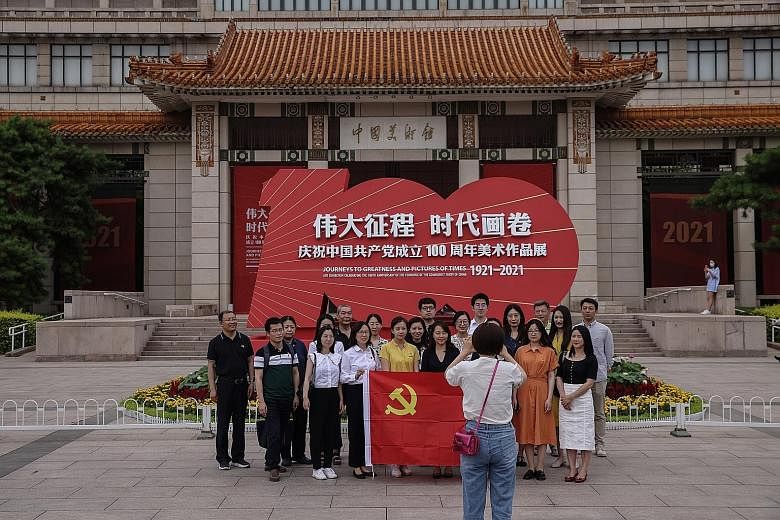 A group photo being taken at the National Art Museum in Beijing last Thursday, in front of a signboard featuring an art exhibition celebrating the 100th anniversary of the founding of the Chinese Communist Party.